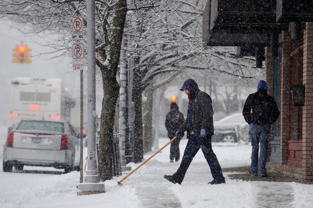 A man shovels the sidewalk in front of several businesses along W. Washington near S. State street on Tuesday morning. Melanie Maxwell I AnnArbor.com